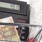 Euronote, Kassenzettel und Tischrechner in einem Einkaufswagenmodell